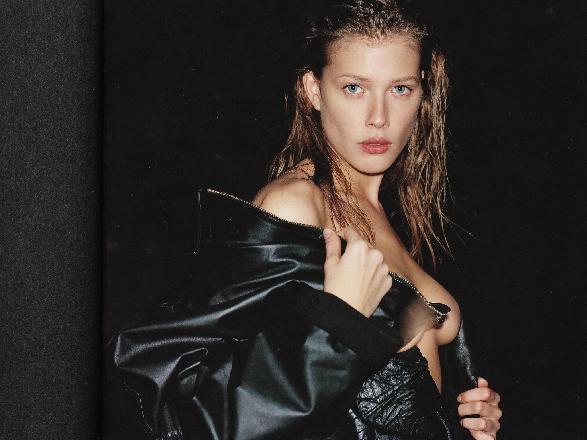 Fashion portrait with wet hair and a black leather jacket against a dark backdrop